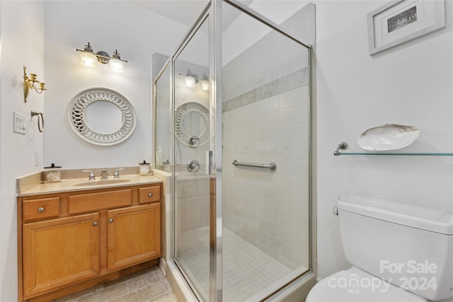 bathroom with vanity, toilet, and a shower with door