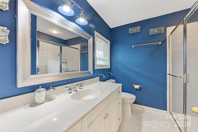 bathroom featuring tile patterned floors, vanity, toilet, and a shower with shower door