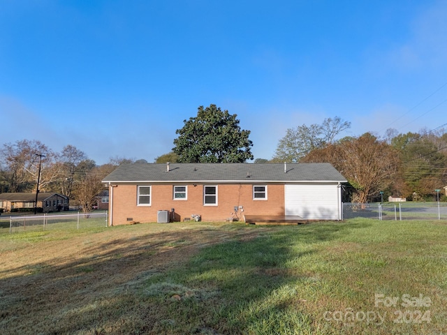 rear view of house featuring central AC unit and a lawn