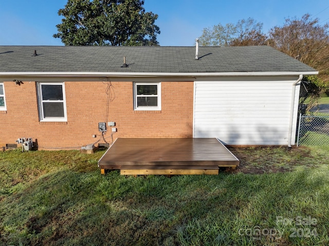 back of property with a deck and a lawn