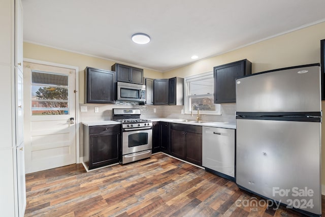 kitchen featuring sink, dark hardwood / wood-style floors, crown molding, decorative backsplash, and appliances with stainless steel finishes