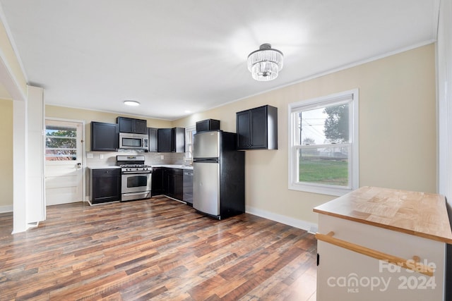 kitchen featuring hardwood / wood-style flooring, ornamental molding, stainless steel appliances, and an inviting chandelier