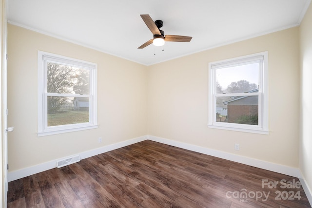 empty room with ceiling fan, a healthy amount of sunlight, crown molding, and dark wood-type flooring