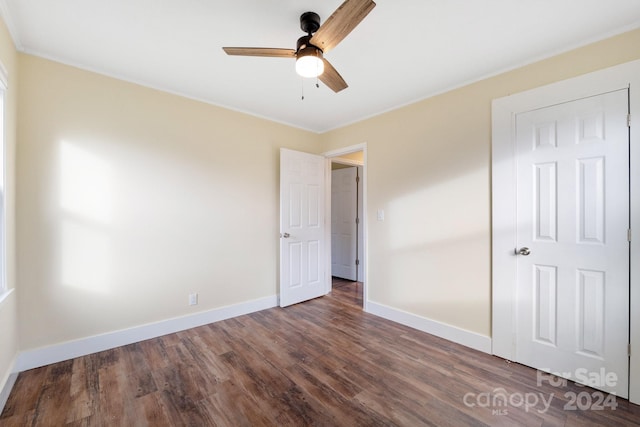 unfurnished bedroom with ceiling fan, dark hardwood / wood-style floors, and crown molding