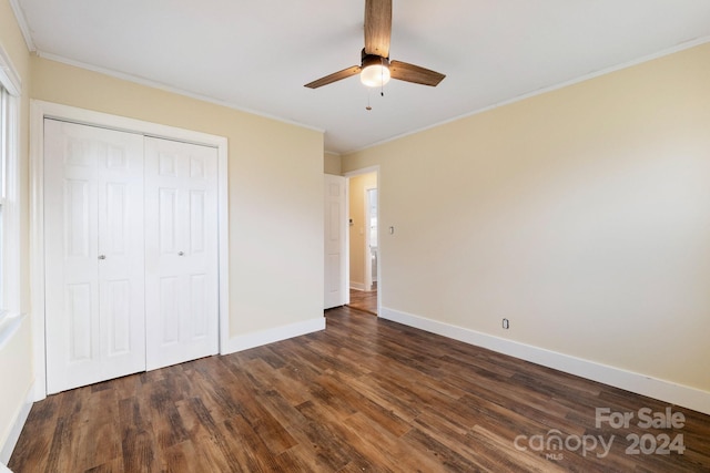 unfurnished bedroom with a closet, dark hardwood / wood-style floors, ceiling fan, and crown molding