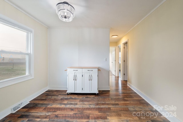 unfurnished dining area featuring dark hardwood / wood-style flooring, crown molding, and an inviting chandelier