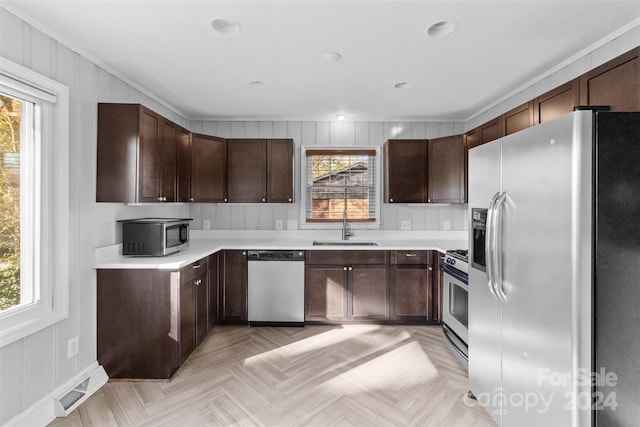 kitchen featuring stainless steel appliances, light parquet floors, a healthy amount of sunlight, and sink