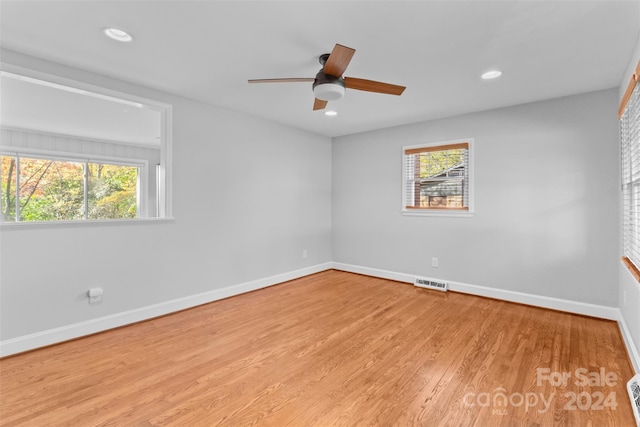 empty room with ceiling fan, a healthy amount of sunlight, and light wood-type flooring