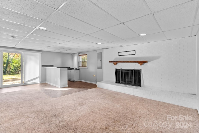 unfurnished living room with carpet flooring, electric panel, a fireplace, and a drop ceiling