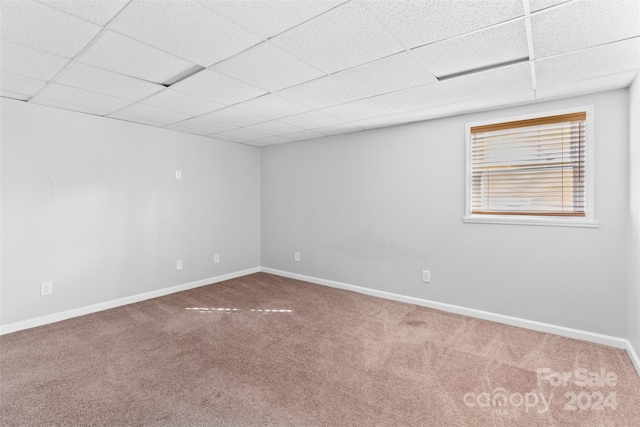 carpeted empty room featuring a paneled ceiling