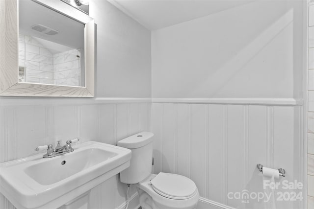1532 Starbrook Dr, Charlotte, NC 28210 - bathroom featuring toilet, a sink, a decorative wall, and a wainscoted wall