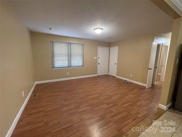 unfurnished room featuring wood-type flooring and a textured ceiling