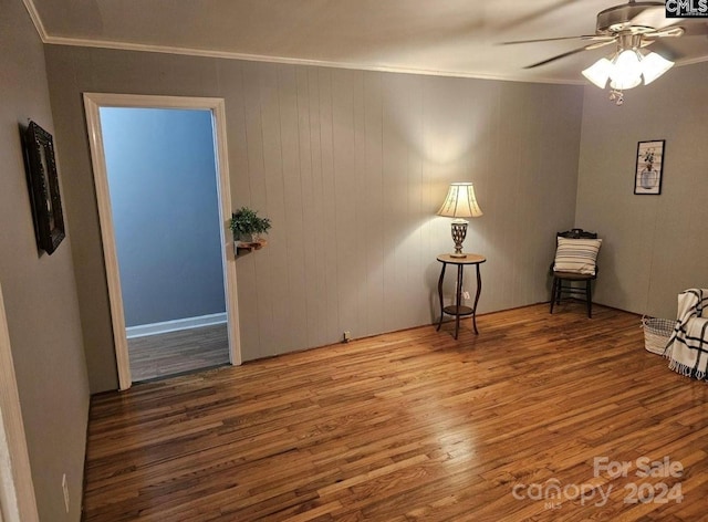 spare room featuring crown molding, wooden walls, ceiling fan, and wood-type flooring