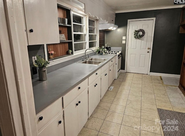 kitchen featuring light tile patterned floors, white stove, white cabinetry, and sink