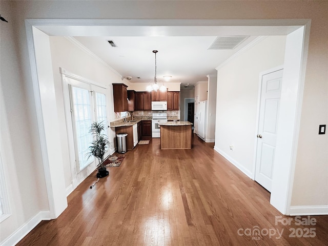 kitchen featuring white appliances, visible vents, a kitchen island, decorative light fixtures, and light countertops