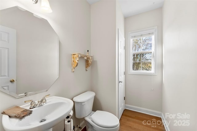 bathroom with toilet, baseboards, a sink, and wood finished floors