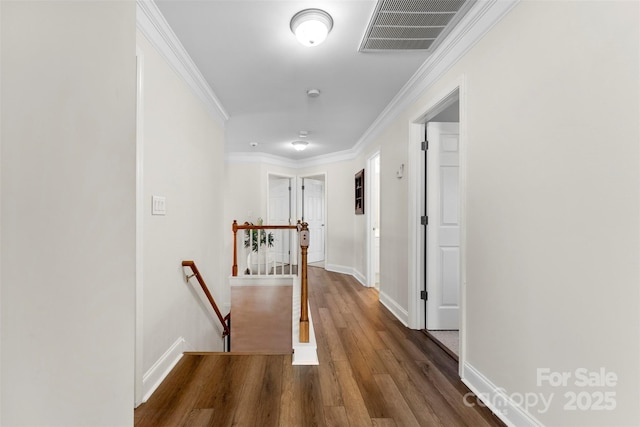 corridor featuring wood finished floors, visible vents, baseboards, an upstairs landing, and crown molding