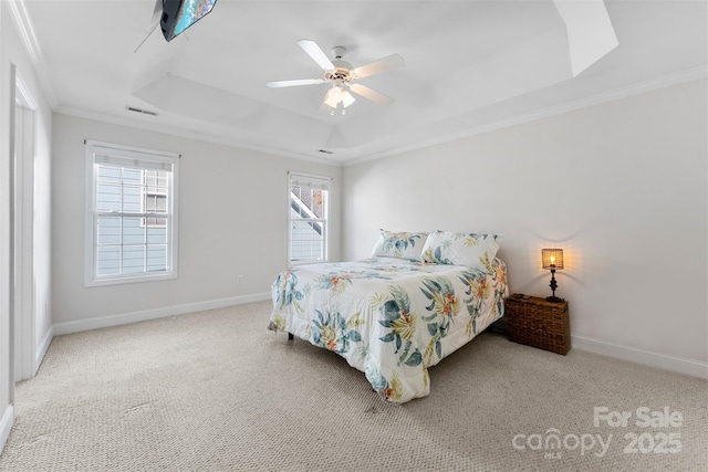 bedroom with ornamental molding, a tray ceiling, multiple windows, and baseboards