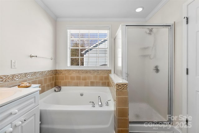 bathroom with a stall shower, ornamental molding, a bath, and vanity