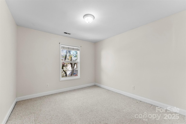 carpeted spare room with visible vents and baseboards