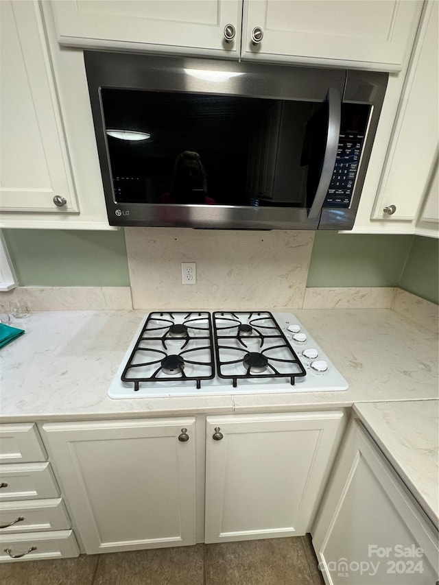 kitchen with white gas cooktop, white cabinets, and light stone countertops