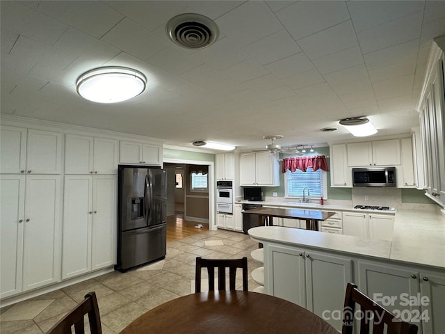 kitchen with kitchen peninsula, white cabinetry, sink, and white appliances