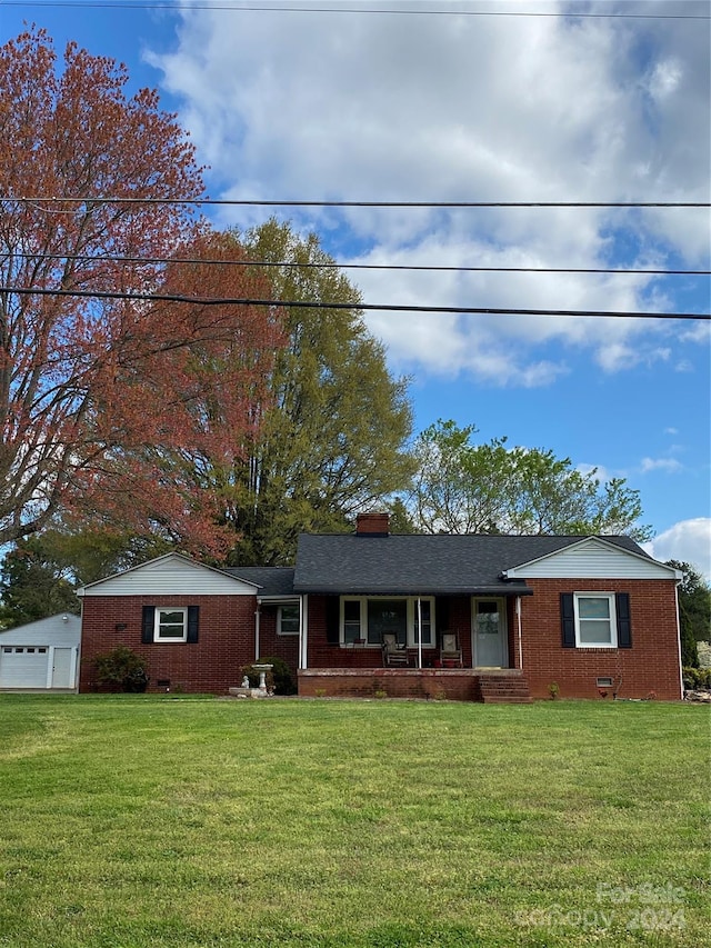 single story home with a front yard, an outbuilding, and covered porch