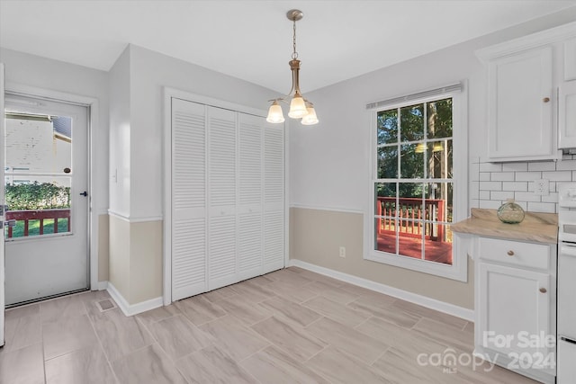 unfurnished dining area featuring an inviting chandelier and plenty of natural light