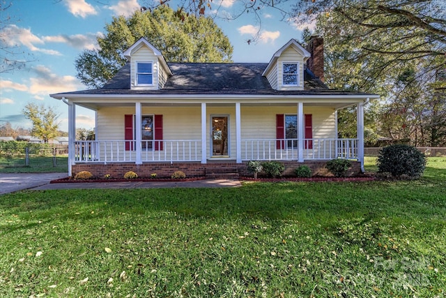 cape cod house featuring a front lawn, fence, covered porch, and a chimney
