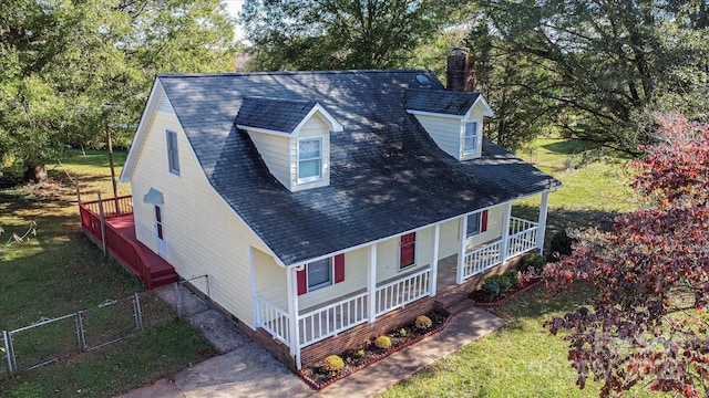exterior space featuring a chimney, a shingled roof, covered porch, and fence