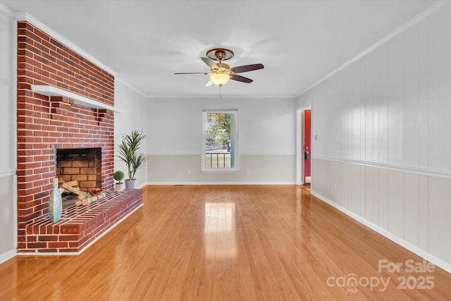 unfurnished living room with a fireplace, wood finished floors, ceiling fan, and ornamental molding