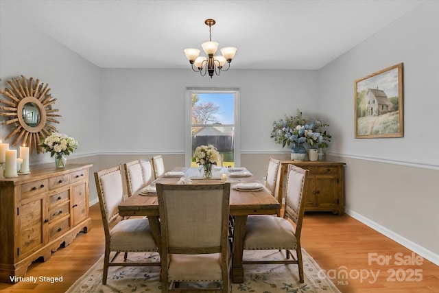 dining area with a chandelier, baseboards, and light wood-style floors