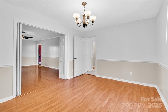 unfurnished room featuring wood finished floors, a chandelier, and baseboards
