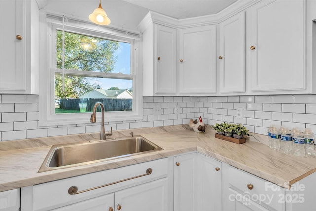kitchen featuring tasteful backsplash, a sink, white cabinetry, and light countertops