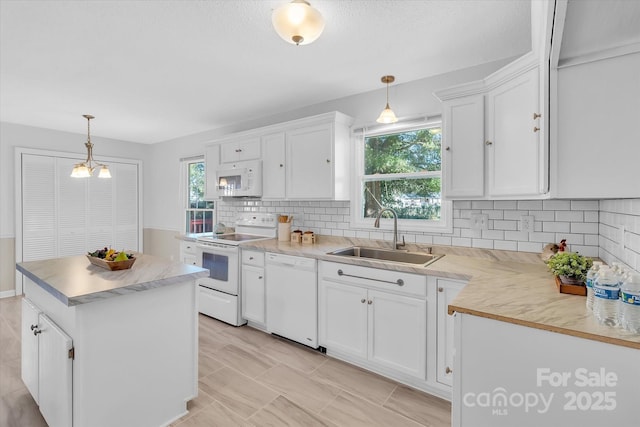 kitchen featuring white cabinetry, a sink, a center island, white appliances, and backsplash