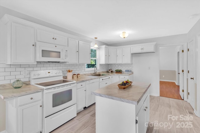 kitchen featuring white cabinetry, white appliances, and a sink