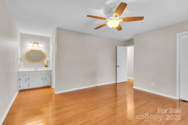 unfurnished bedroom with light wood finished floors, ensuite bathroom, a ceiling fan, and baseboards