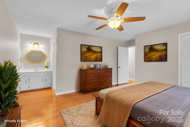bedroom featuring ensuite bathroom, a ceiling fan, light wood finished floors, and baseboards
