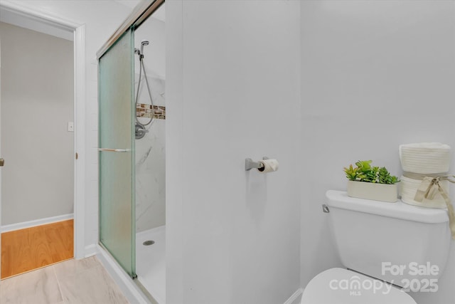 full bathroom featuring toilet, a stall shower, and baseboards