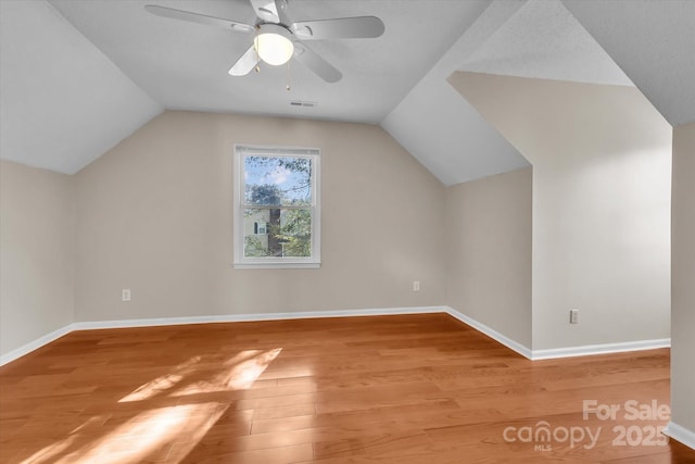 additional living space featuring wood finished floors, vaulted ceiling, baseboards, visible vents, and a ceiling fan