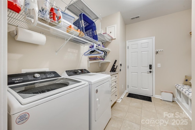 clothes washing area featuring cabinets, separate washer and dryer, and light tile patterned floors