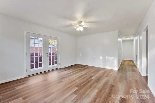 empty room featuring french doors, light wood-type flooring, ceiling fan, and crown molding