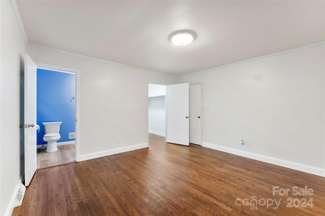 unfurnished bedroom featuring connected bathroom, crown molding, and wood-type flooring