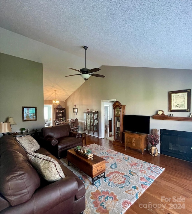 living room featuring hardwood / wood-style flooring, ceiling fan, lofted ceiling, and a textured ceiling