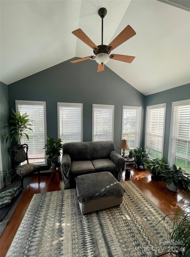 living room with ceiling fan, a healthy amount of sunlight, dark wood-type flooring, and vaulted ceiling