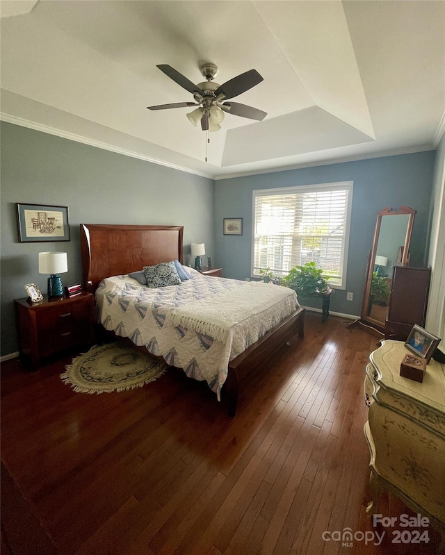 bedroom with a raised ceiling, crown molding, ceiling fan, and dark wood-type flooring