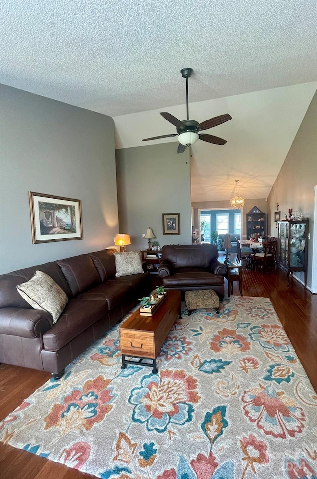 living room featuring a textured ceiling, ceiling fan with notable chandelier, hardwood / wood-style flooring, and lofted ceiling