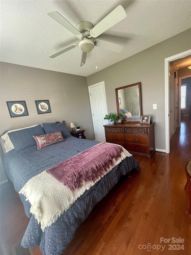 bedroom featuring ceiling fan, dark wood-type flooring, and a textured ceiling