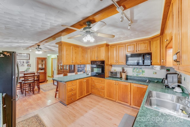 kitchen with sink, tasteful backsplash, kitchen peninsula, black appliances, and light wood-type flooring