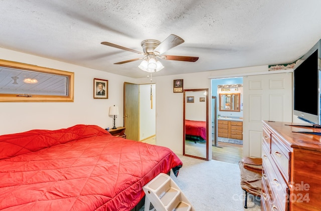 carpeted bedroom featuring ensuite bath, ceiling fan, and a textured ceiling